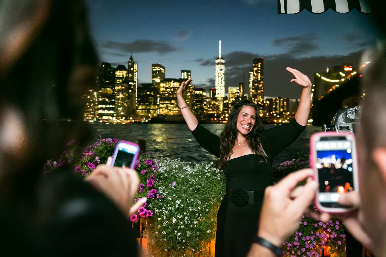 Female guest taking photo outside at night at a River Café wedding in Brooklyn