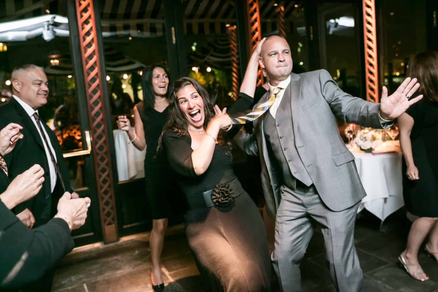 Female guest dancing crazy with groom at a River Café wedding in Brooklyn