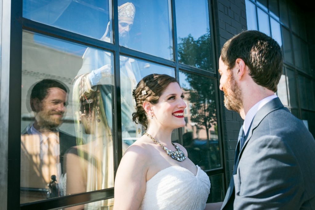 Bride and groom leaning in front of glass window