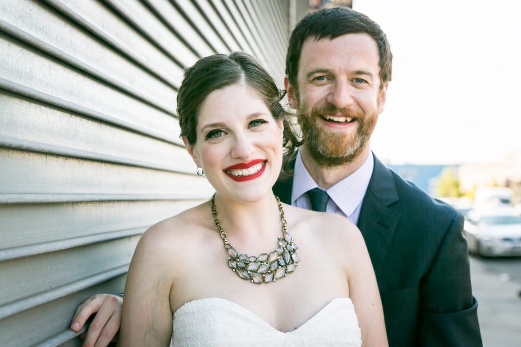 Bride and groom in front of metal gate at a Bell House wedding anniversary party