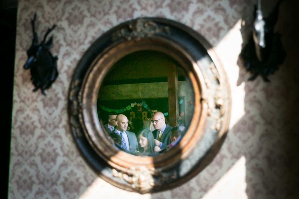 Reflection in round mirror of guests at a Bell House wedding anniversary party
