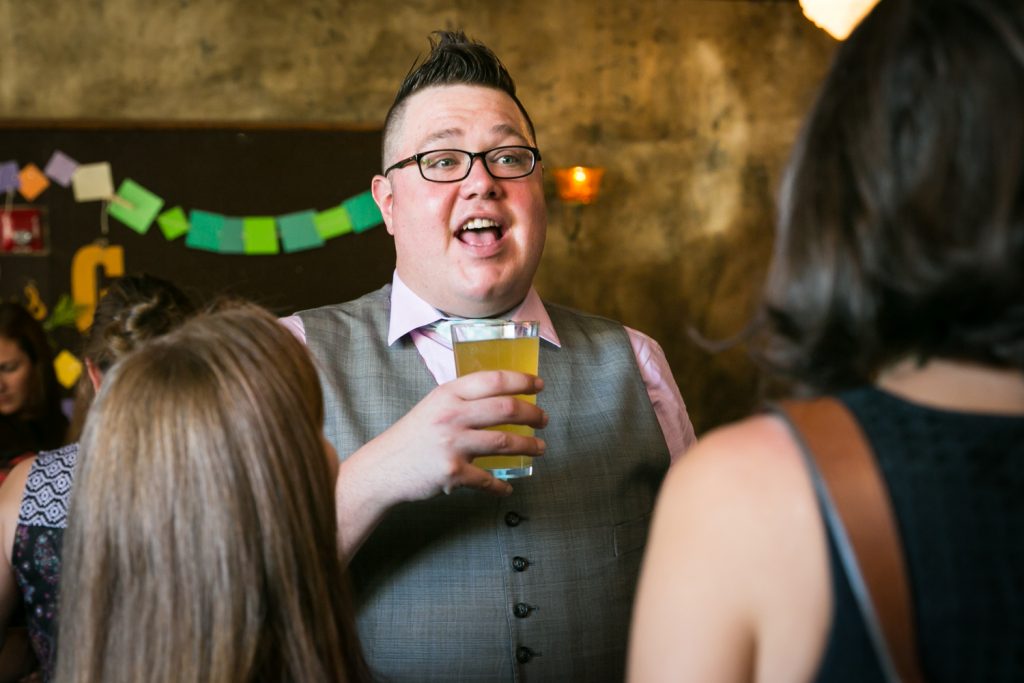 Male guest holding glass of beer at a Bell House wedding anniversary party