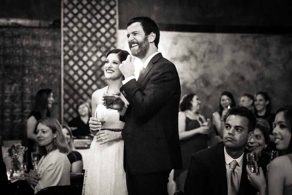 Black and white photo of bride and groom listening to speeches