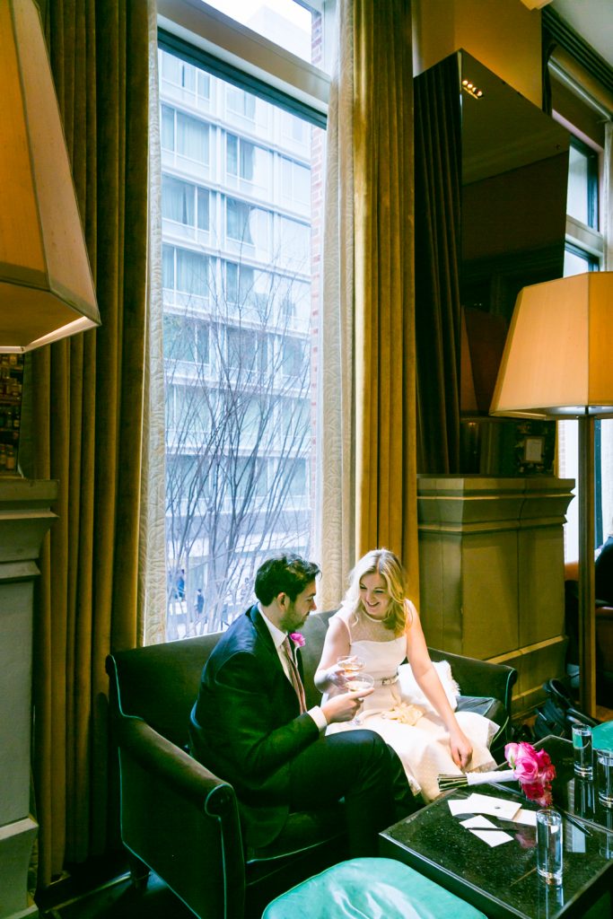 Bride and groom drinking champagne on a sofa in the Soho Grand Hotel
