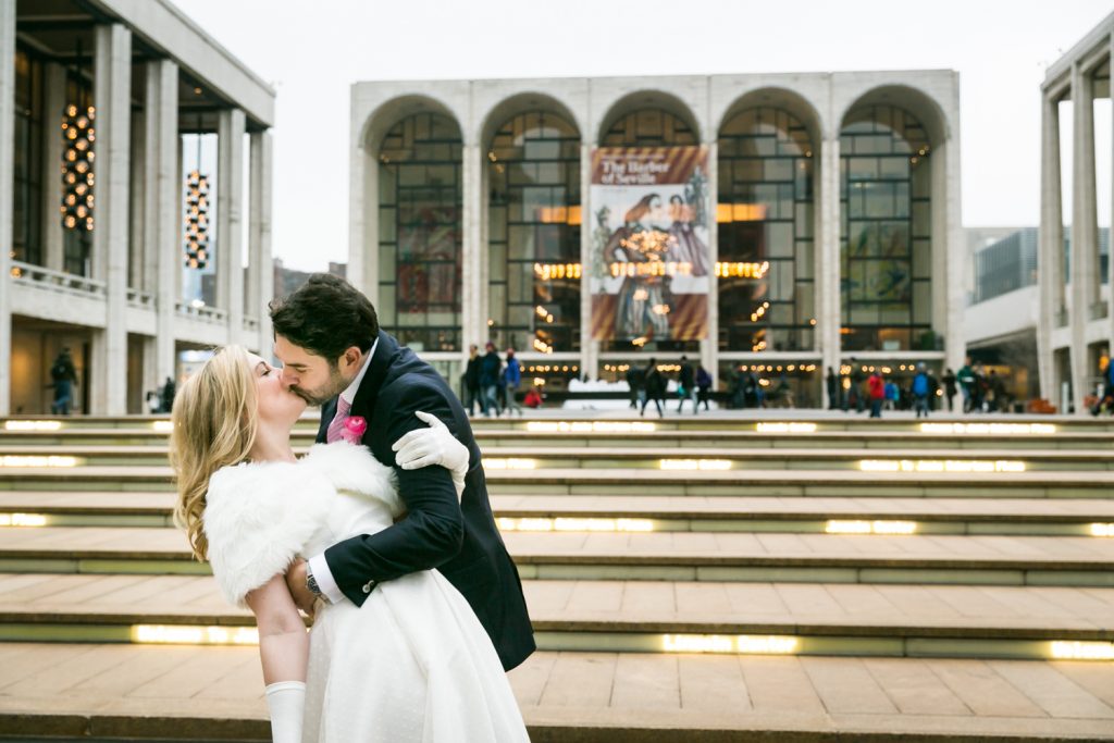 Bride and groom kissing on the steps of Lincoln Center