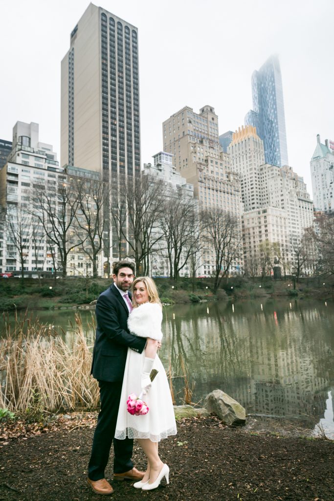 Bride and groom posed on edge of Central Park pond