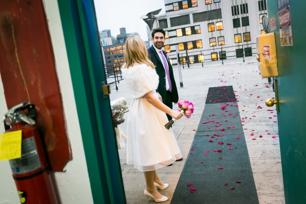 Bride and groom standing on rose petal-strewn carpet at a Grand Hyatt Hotel rooftop wedding