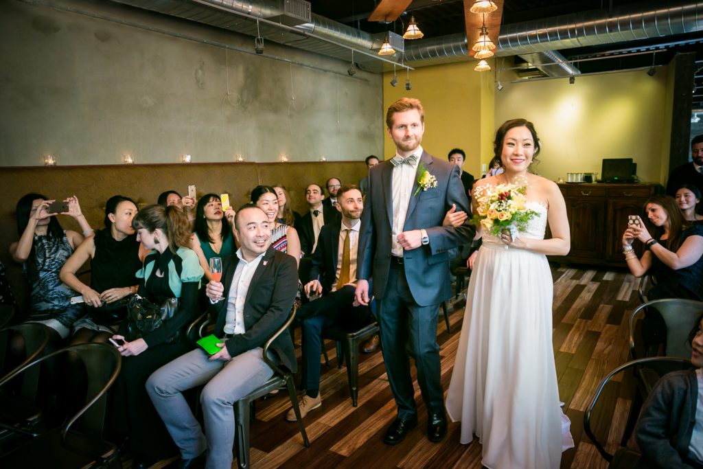 Bride and groom walking down aisle during ceremony at an Astoria restaurant wedding