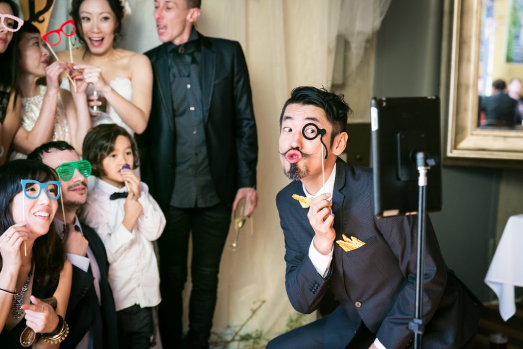 Guests clowning around in front of photo booth at an Astoria restaurant wedding