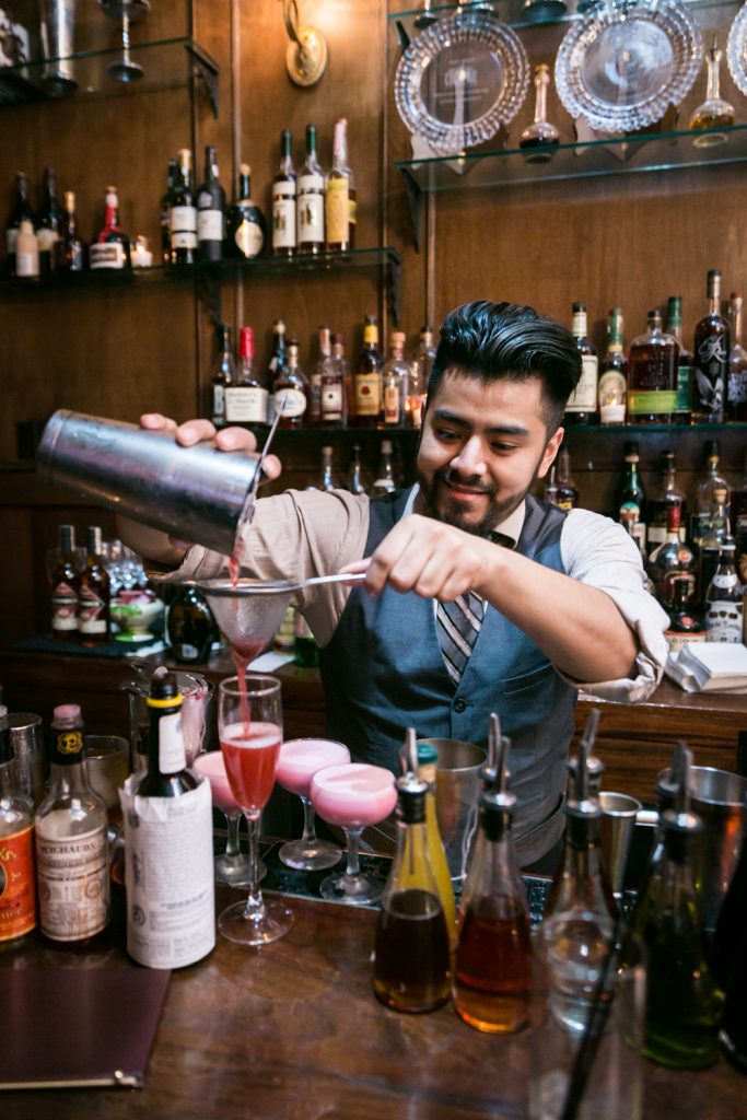 Bartender making cocktail at bar at a Clover Club wedding