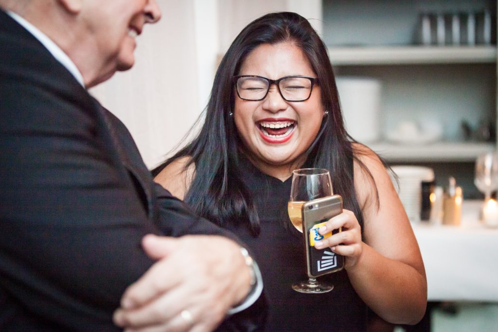 Female guest holding wine glass and laughing at wedding reception