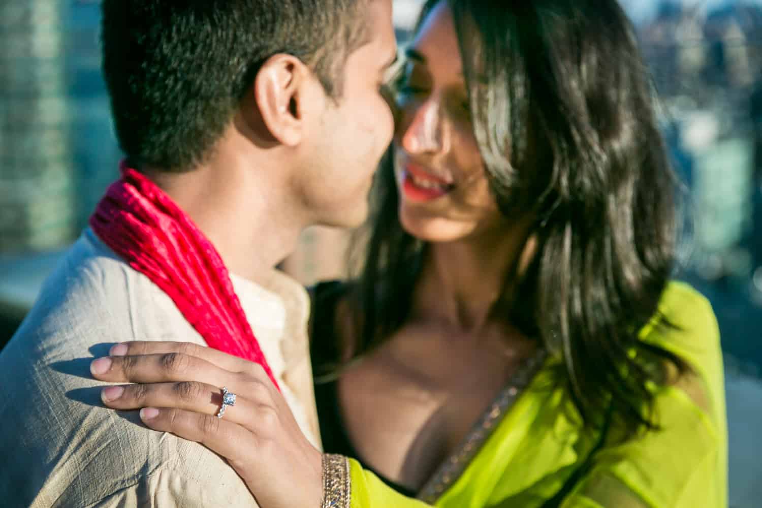 Woman's hand on man's shoulder wearing engagement ring and traditional Indian attire