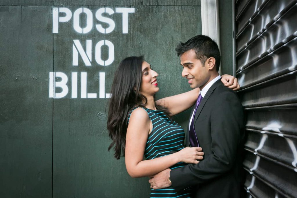 Couple hugging in front of 'post no bills' wall in Tribeca