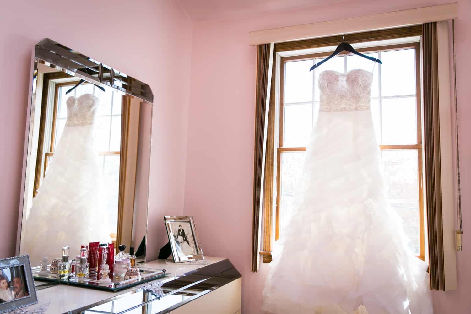 Wedding dress hanging in window and reflected in mirror for an article called 'Do you need a second photographer?'