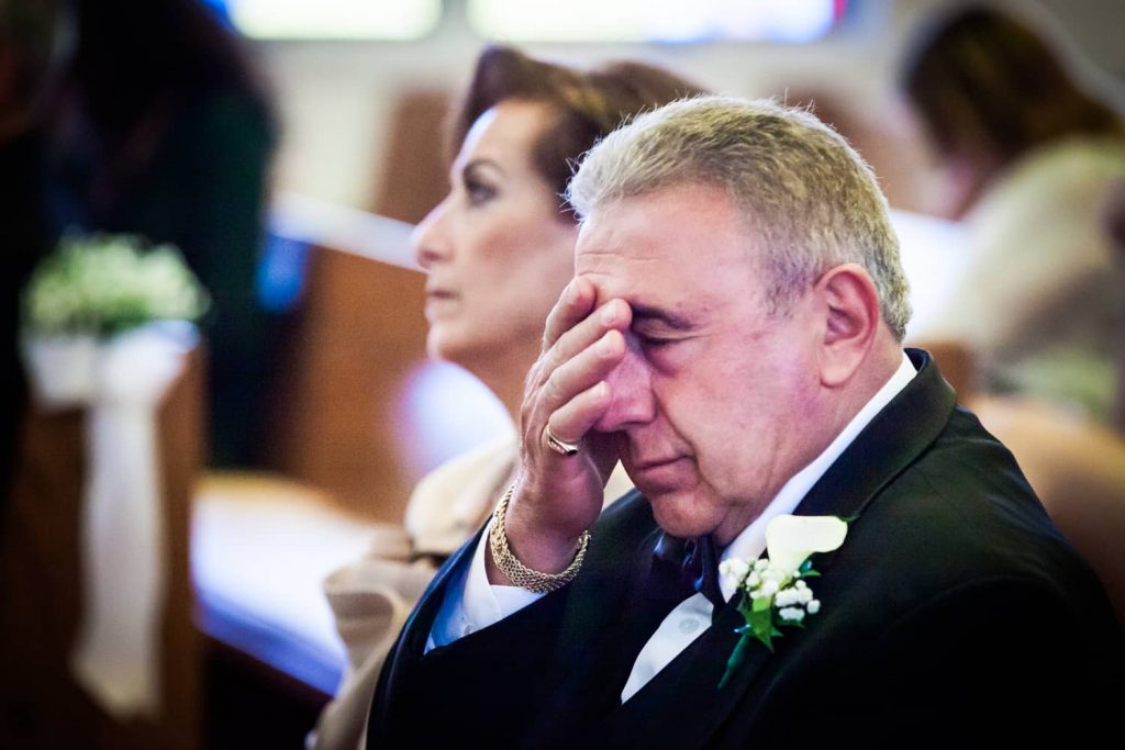 Father wiping away tears in Eastern Orthodox wedding ceremony