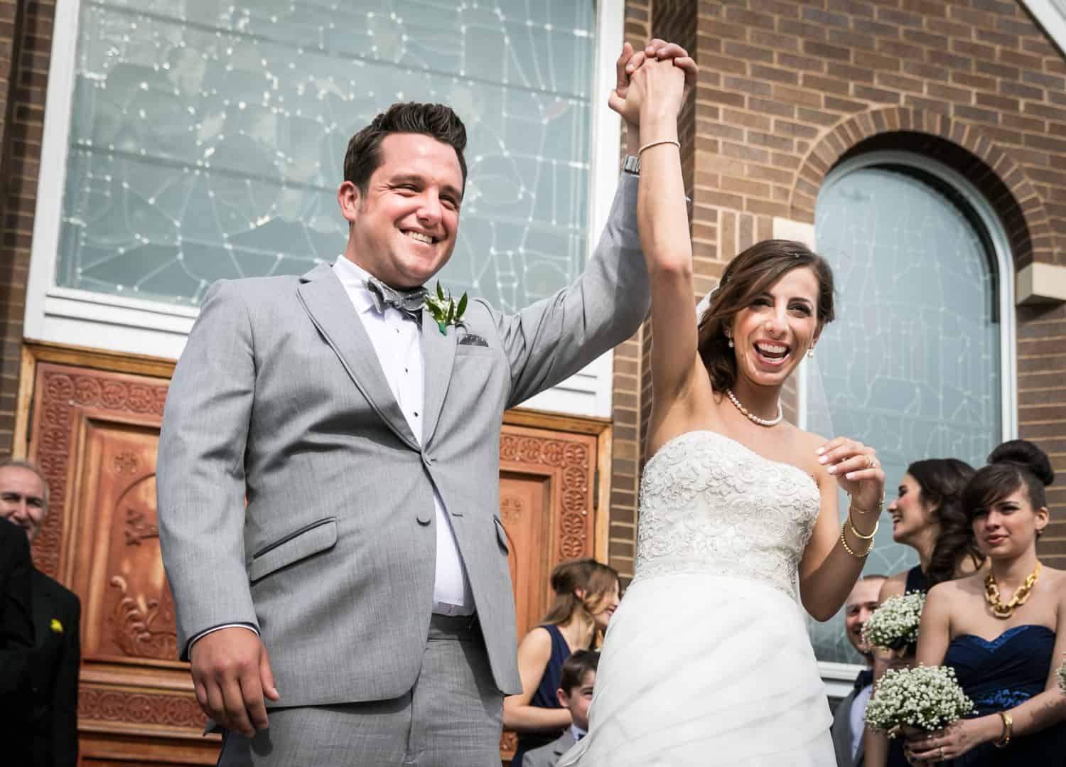 Bride and groom holding hands in the air for an article called 'Do you need a second photographer?'
