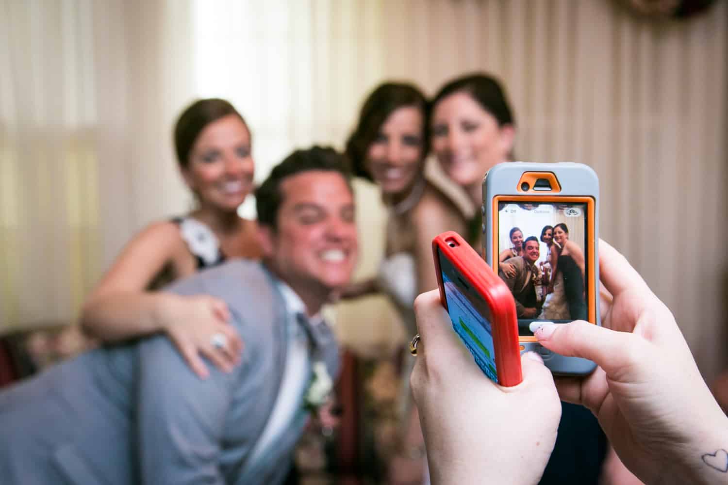 Hands taking photo of bridal party with cell phone