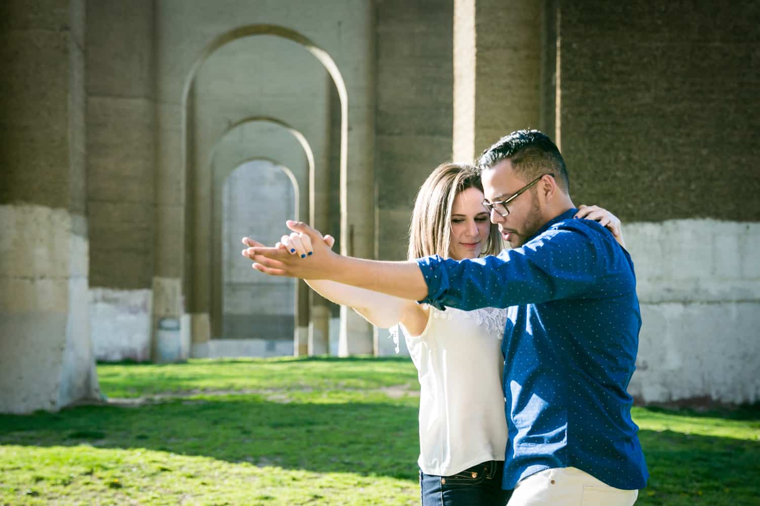 Couple dancing in front of stone arches during an Astoria Park engagement shoot