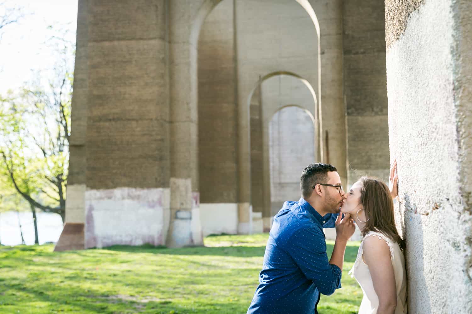 Couple kissing in front of stone arches during an Astoria Park engagement shoot