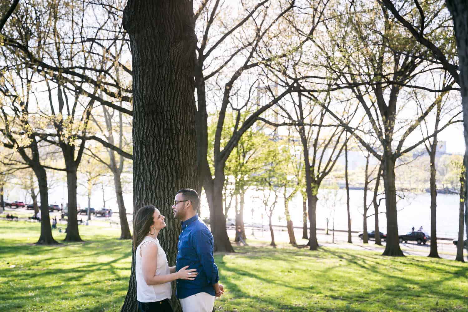 Couple hugging in front of tree during an Astoria Park engagement shoot