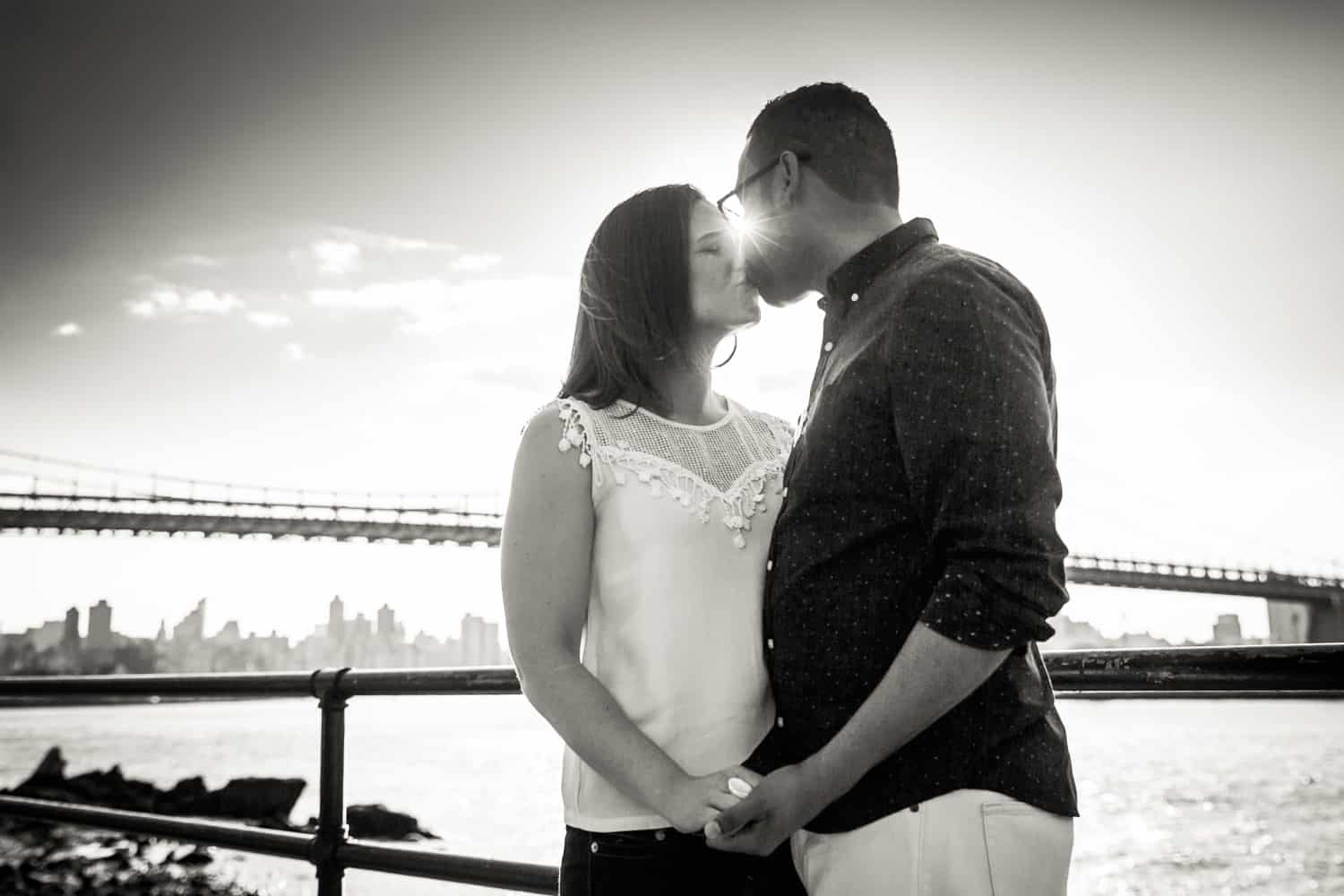 Black and white photo of couple kissing with sunlight in between
