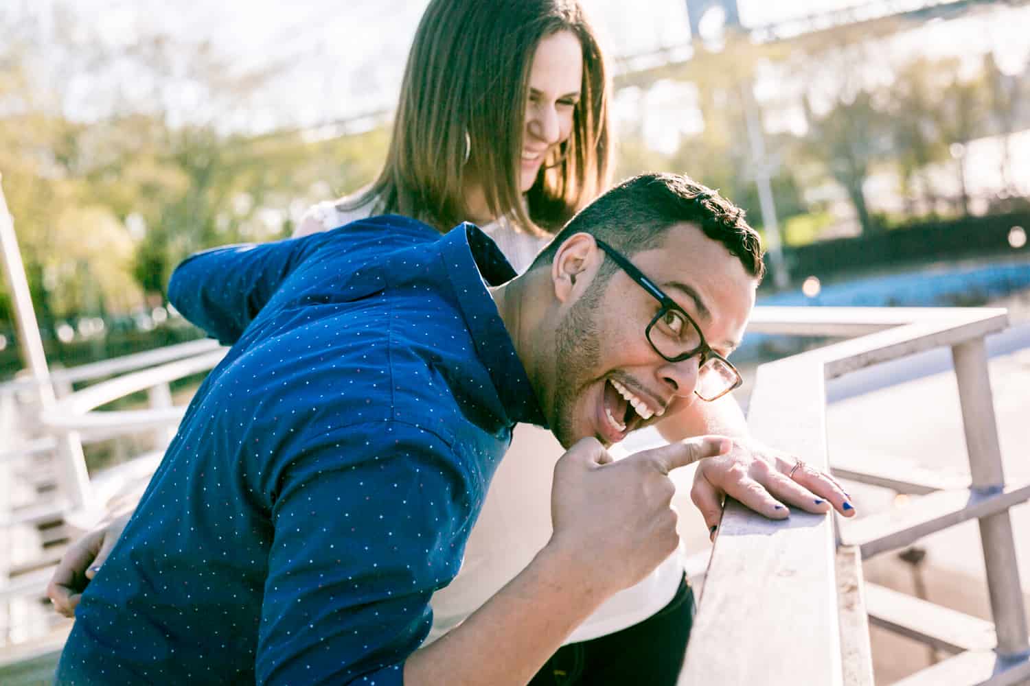 Man pointing to woman's engagement ring on railing during an Astoria Park engagement shoot
