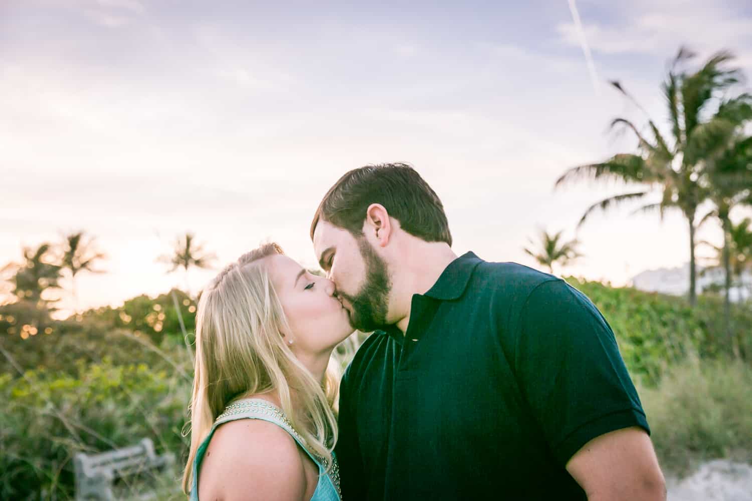 Couple kissing in front of beach during a Coral Cove Park engagement shoot