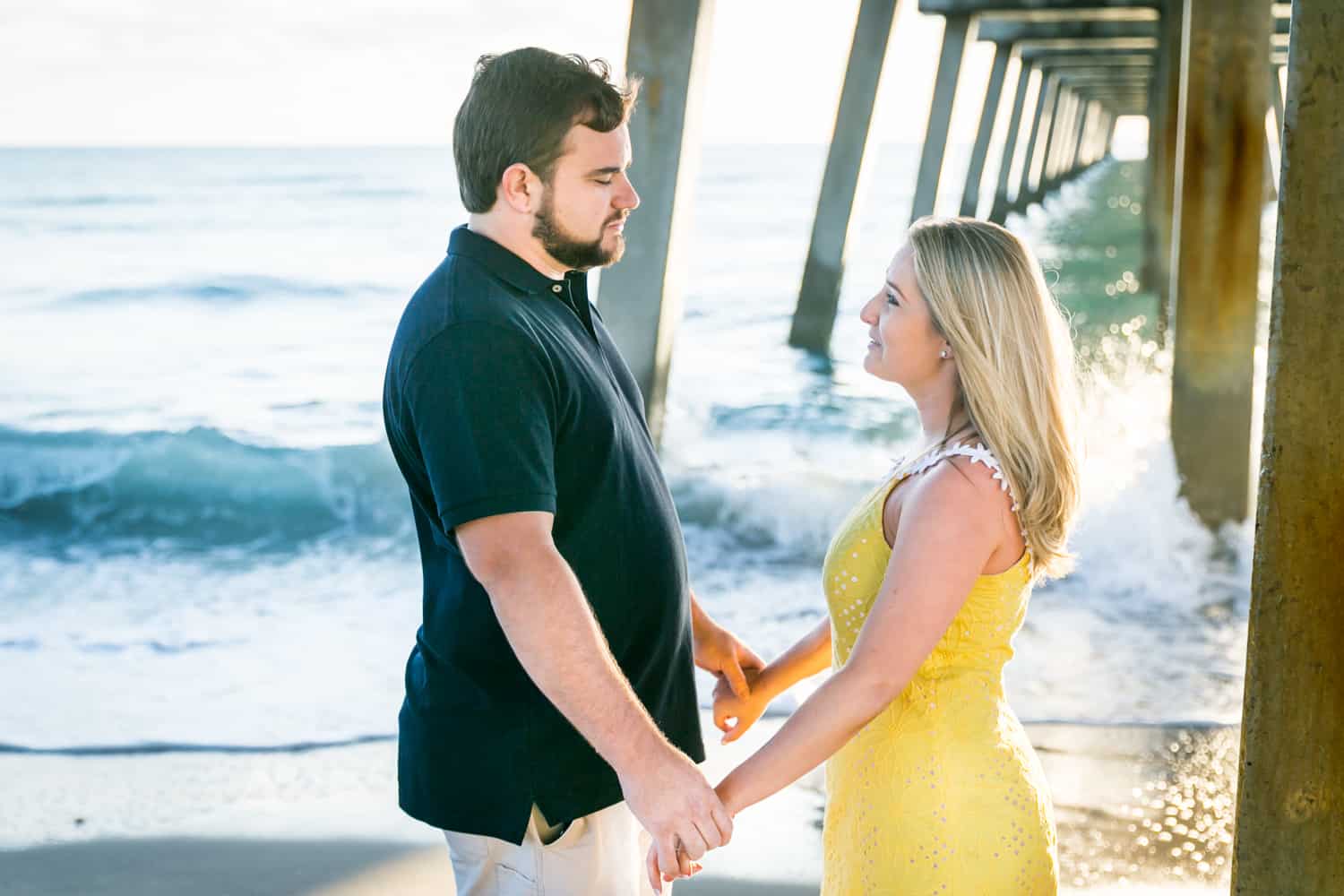 Couple holding hands under dock during a Coral Cove Park engagement shoot