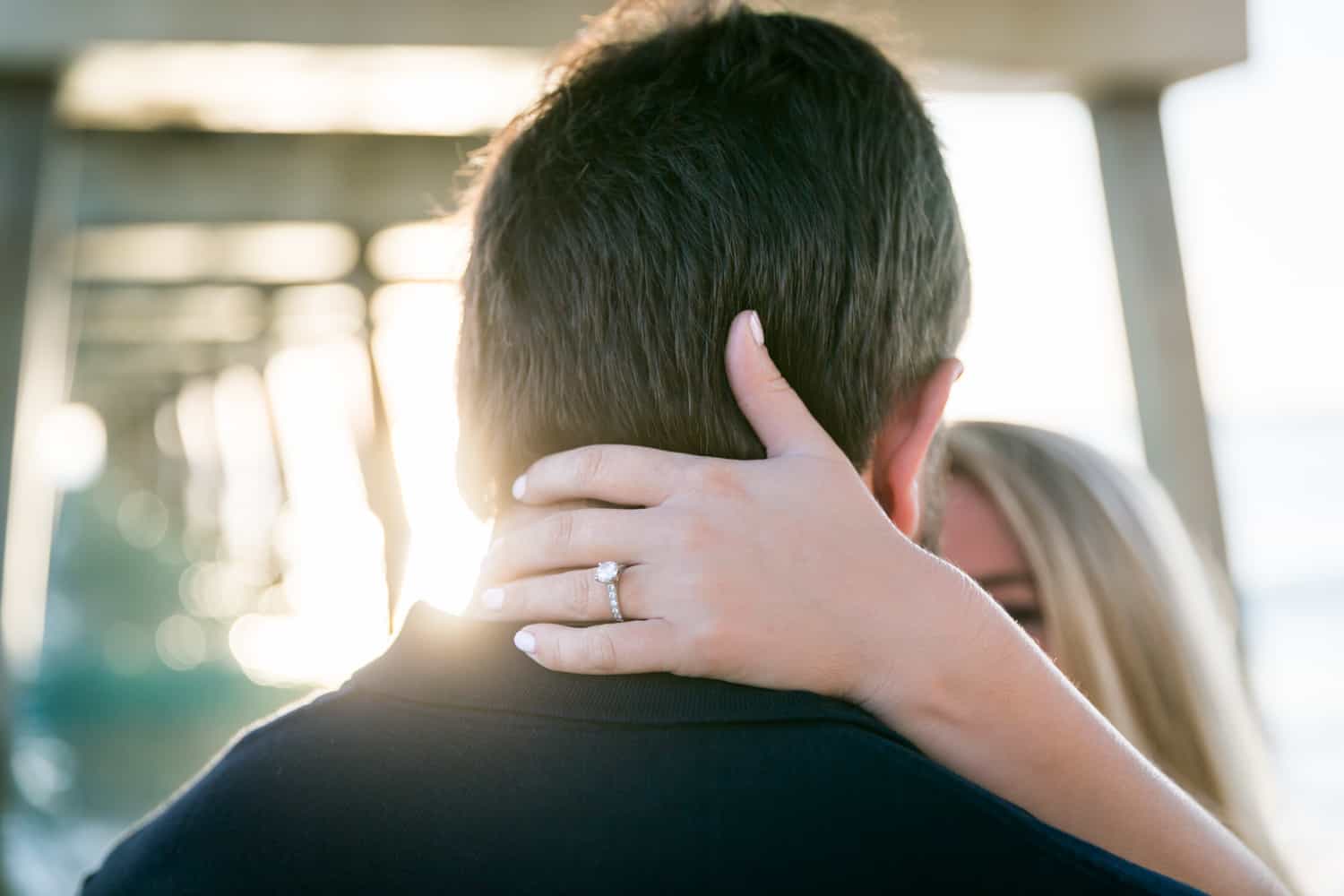 Woman's hand with engagement ring on back of man's head