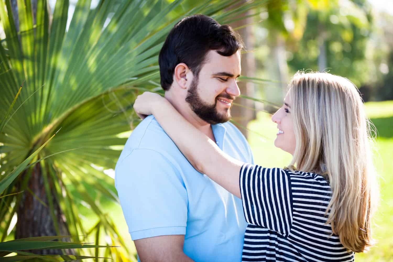 Couple hugging in front of palm frond