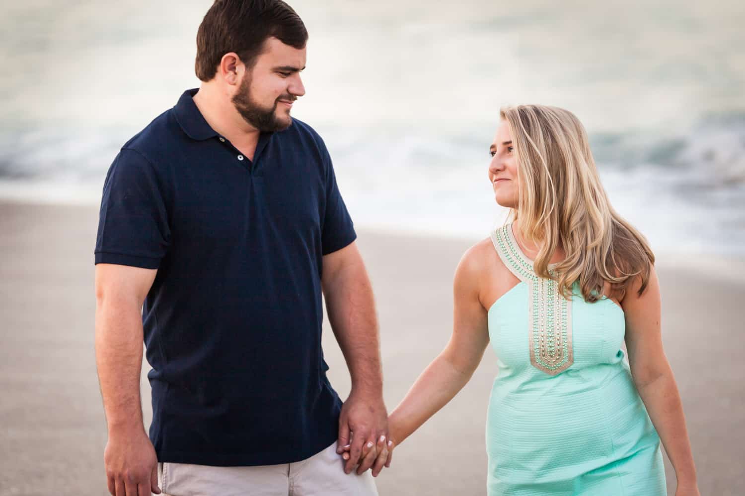 Couple holding hands on beach during a Coral Cove Park engagement shoot