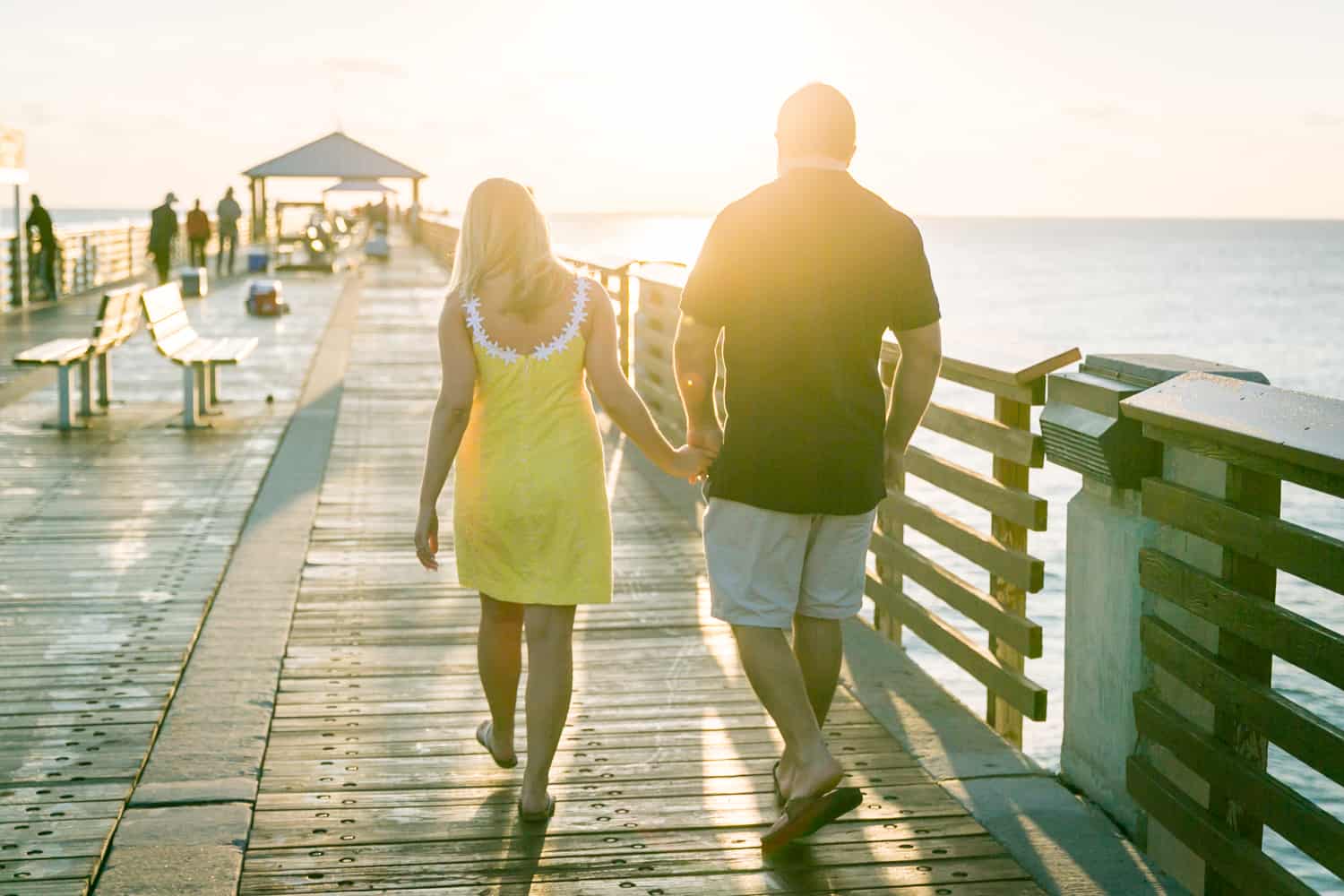 Couple holding hands and walking on pier during a Coral Cove Park engagement shoot