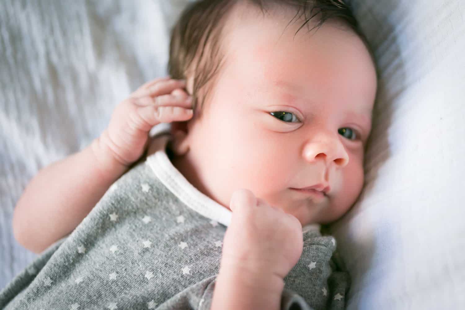 Newborn baby wearing grey polka dot onesie