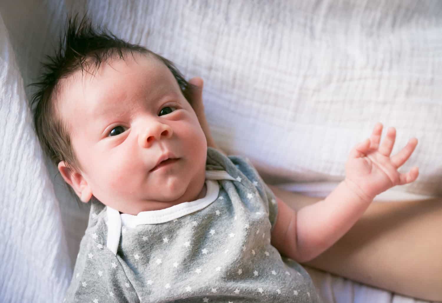 Newborn baby wearing grey polka dot onesie