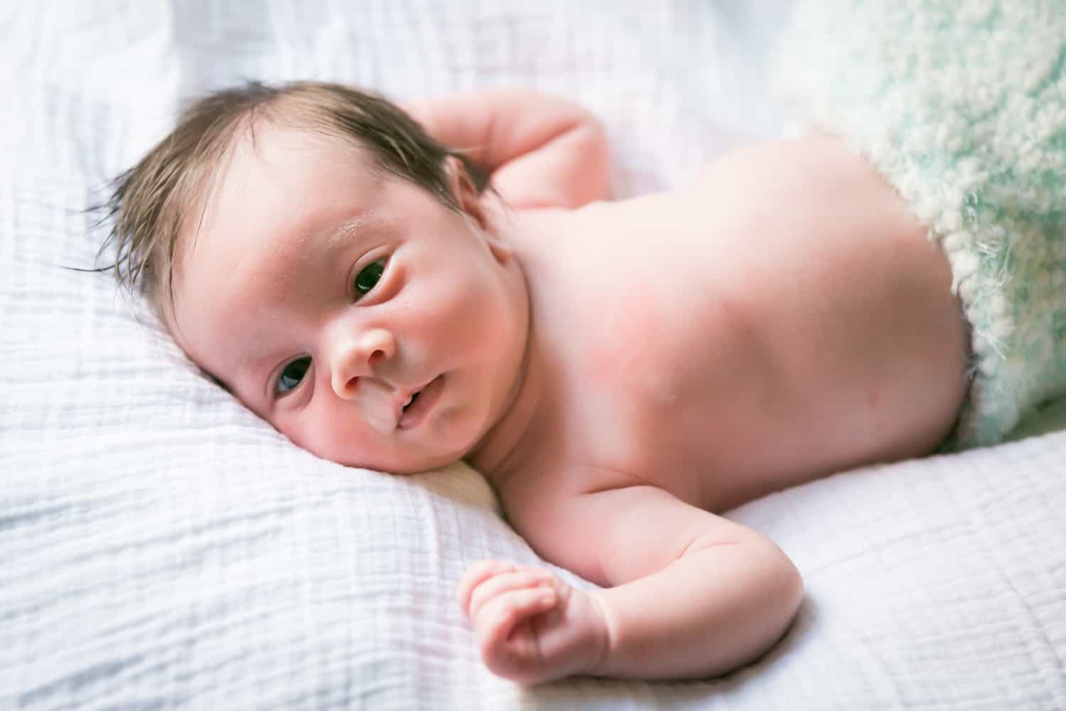 Newborn baby on white sheet