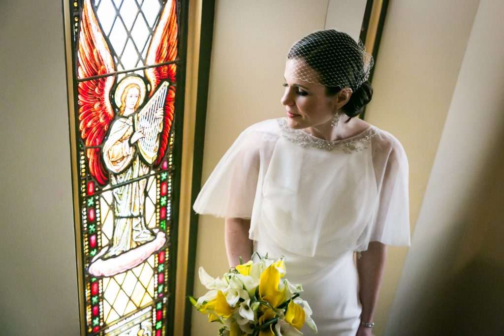 Bride with bouquet looking at stained glass window