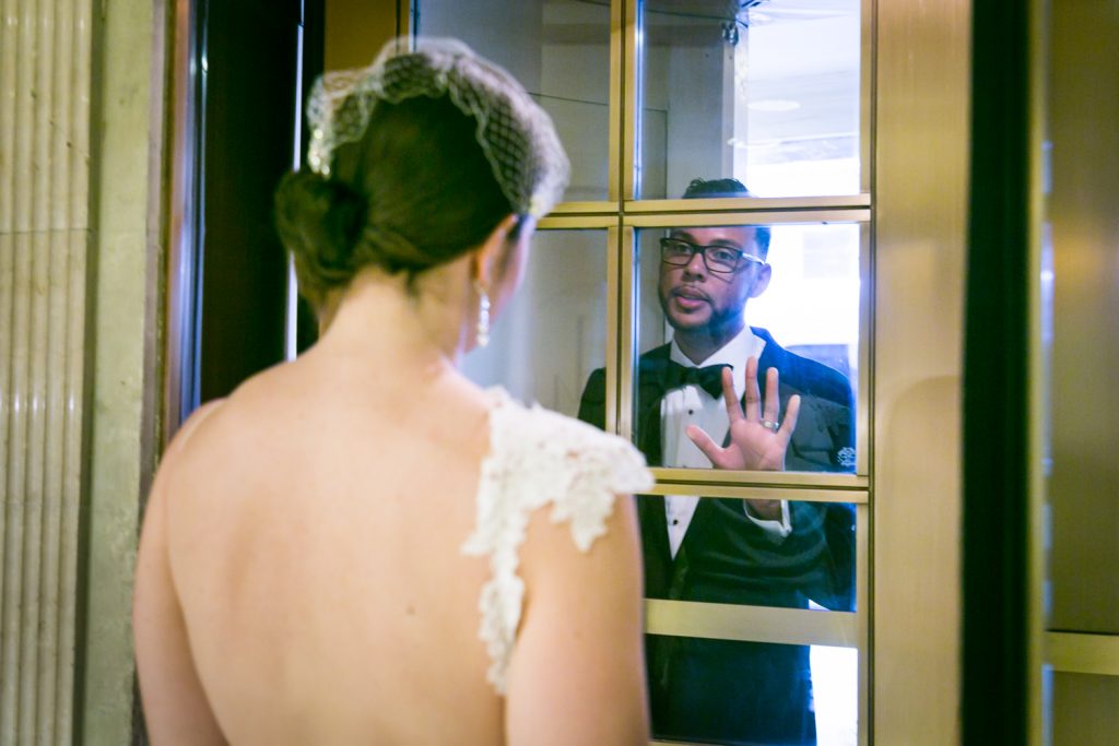 Bride looking at groom through turnstile door in Roosevelt Hotel wedding photo