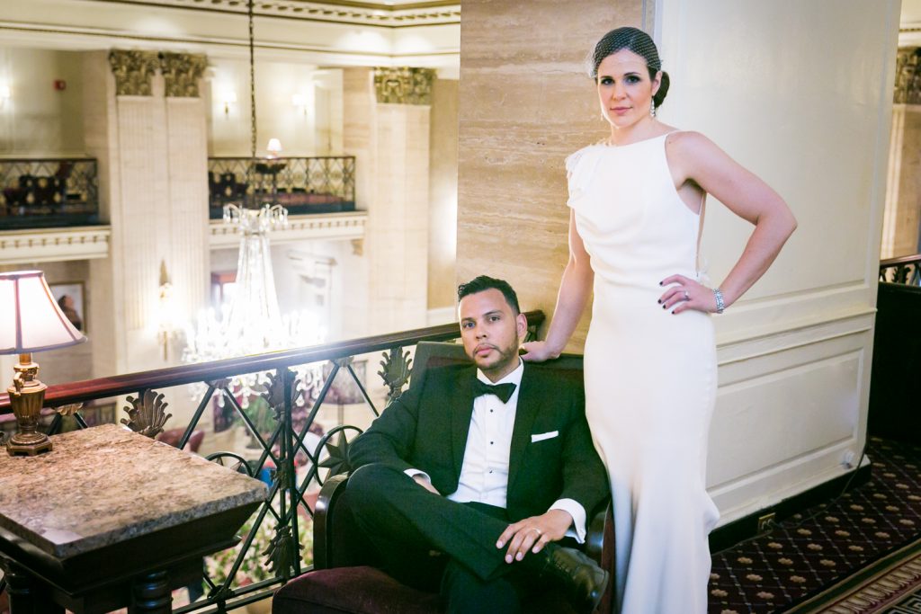 Bride standing above sitting groom in Roosevelt Hotel wedding photo