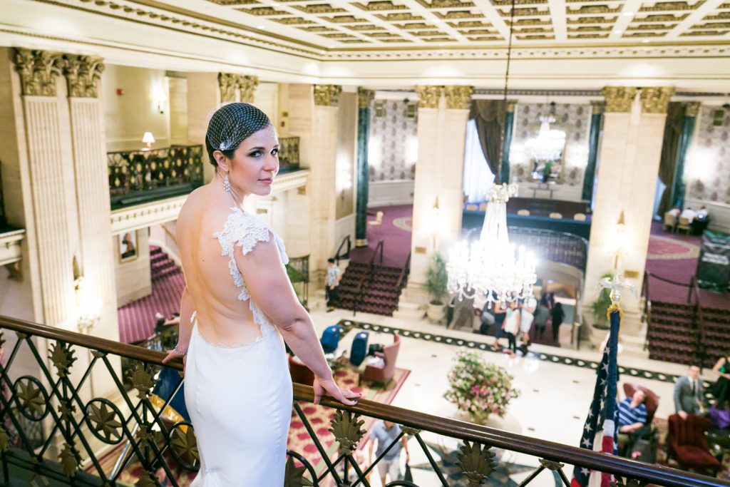 Bride looking back at camera with hotel lobby in background in Roosevelt Hotel wedding photo