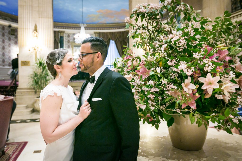 Bride pulling groom to her against table with flowers in Roosevelt Hotel wedding photo