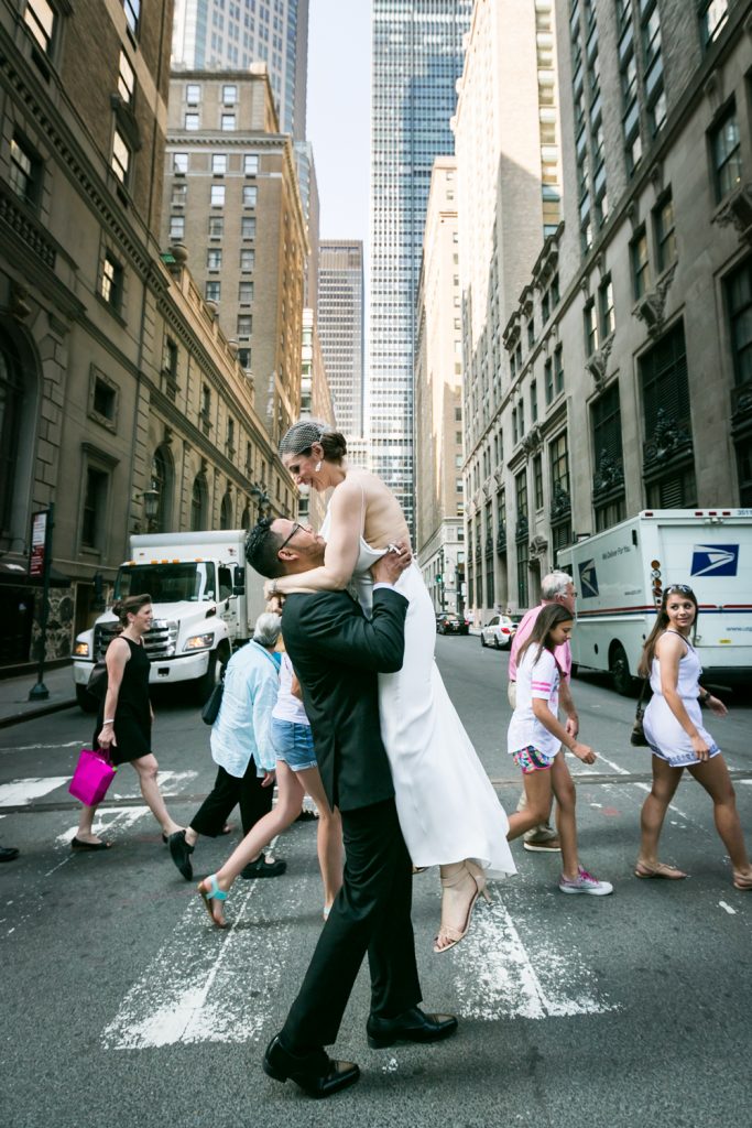 Groom lifting up bride in Manhattan crosswalk