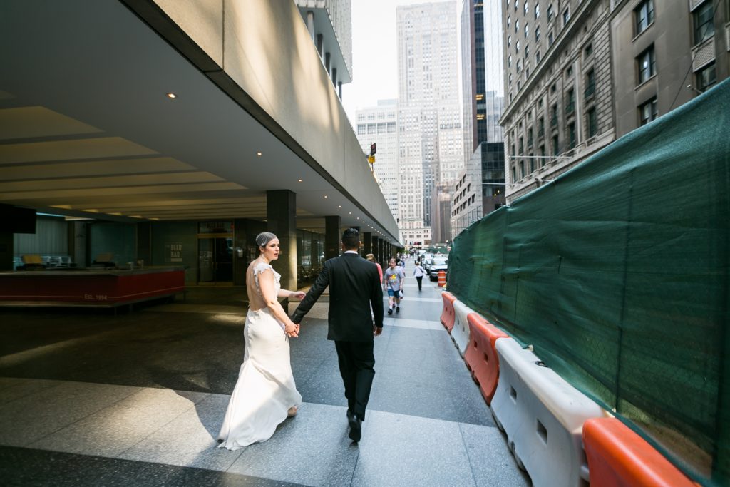 Groom leading bride down sidewalk outside Grand Central Terminal