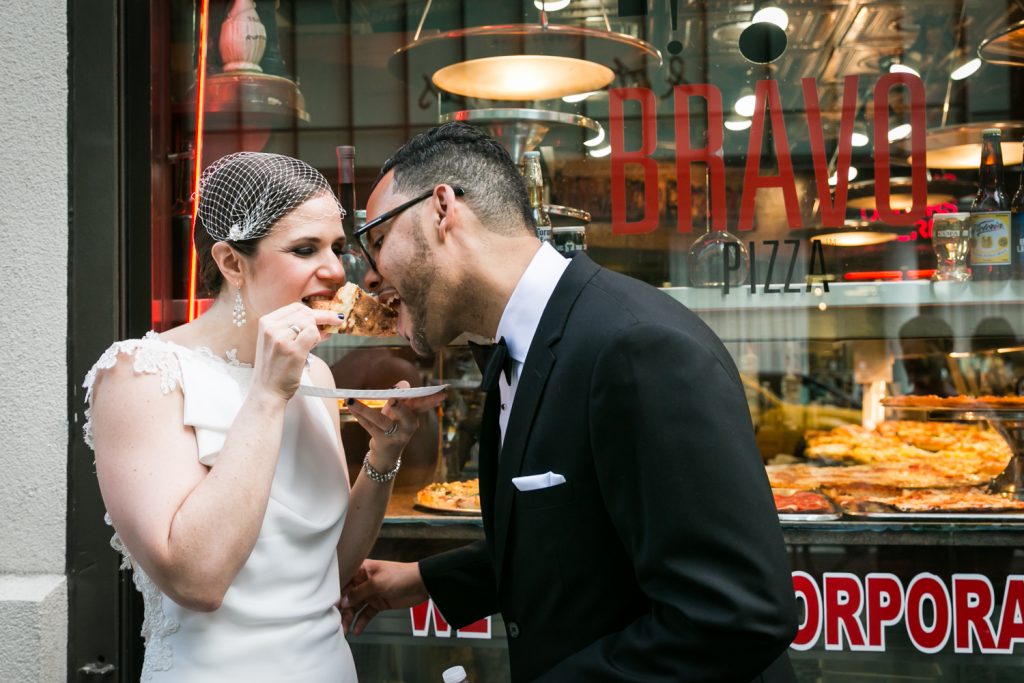 Bride and groom eating pizza on the street