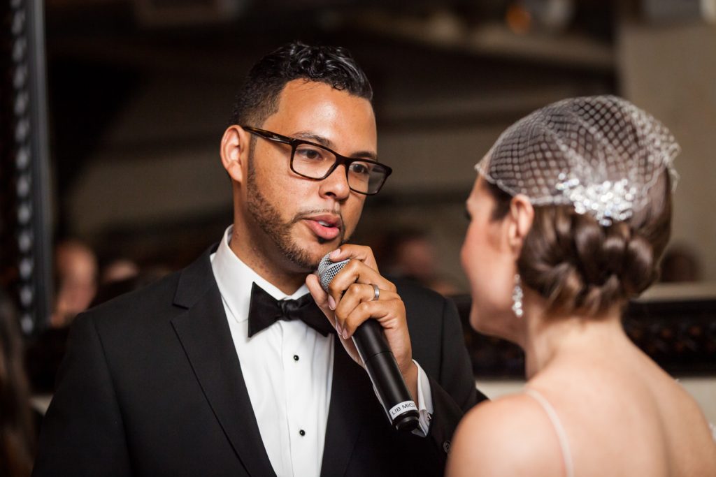 Groom using microphone to speak to bride