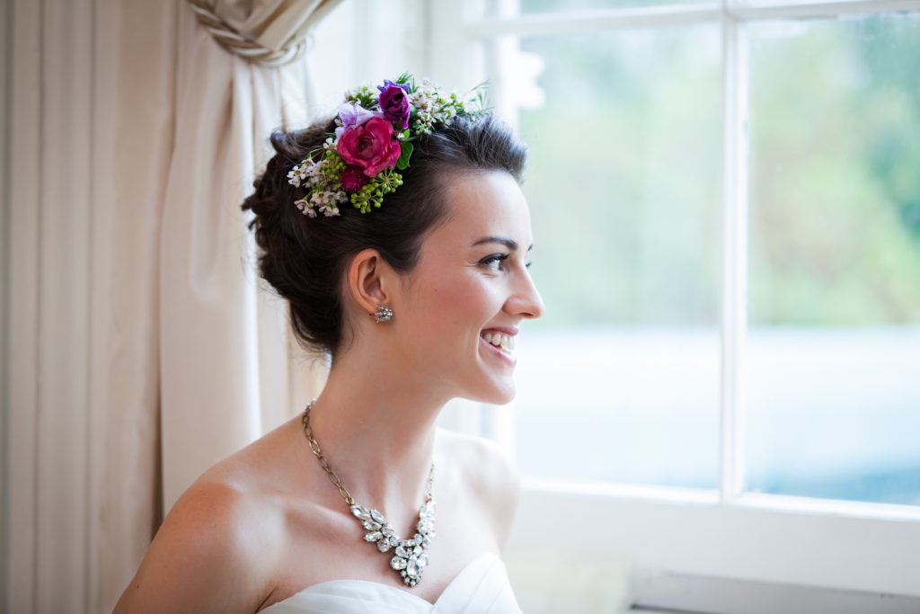 Bride wearing flower crown looking out window at a Snug Harbor wedding