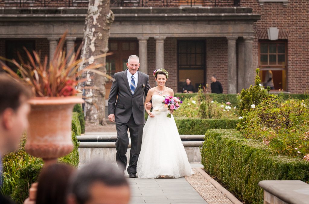 Bride and father walking down aisle in Tuscan Garden at a Snug Harbor wedding