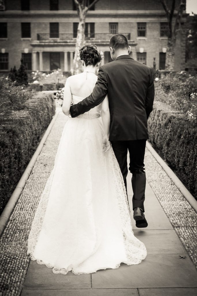 Black and white photo of bride and groom walking down aisle in Tuscan Garden