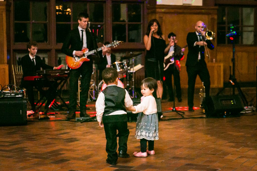 Two little kids holding hands in front of live band at a Snug Harbor wedding