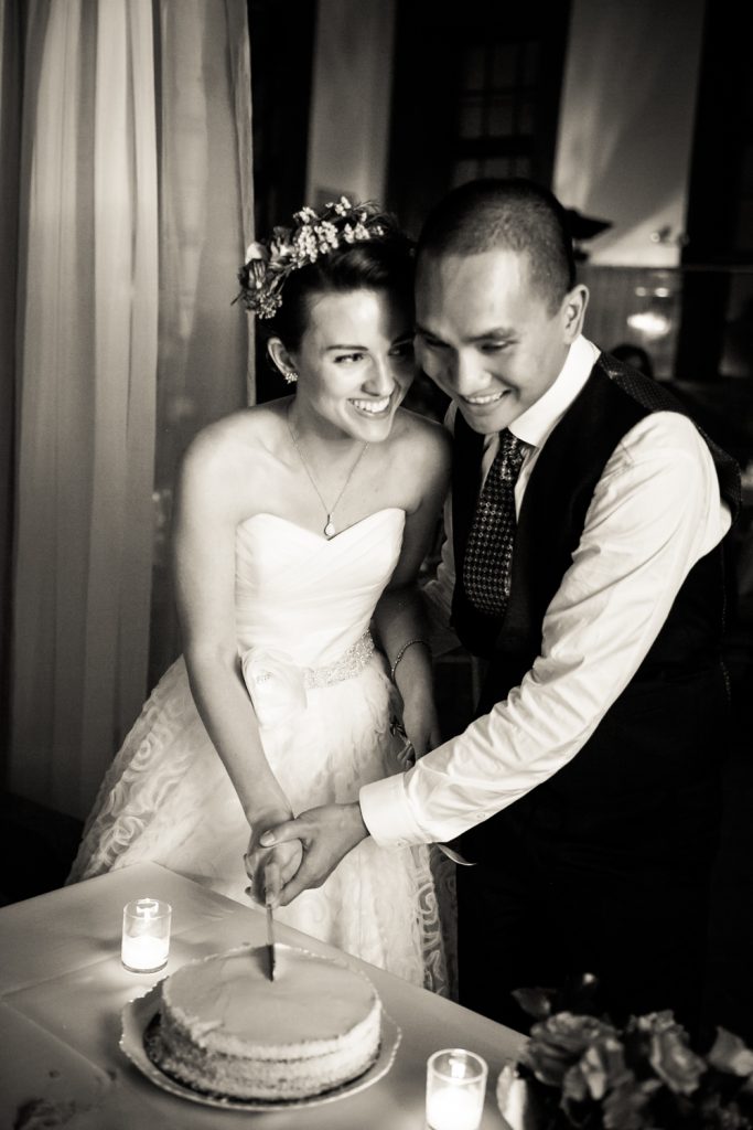 Black and white photo of bride and groom cutting cake at a Snug Harbor wedding