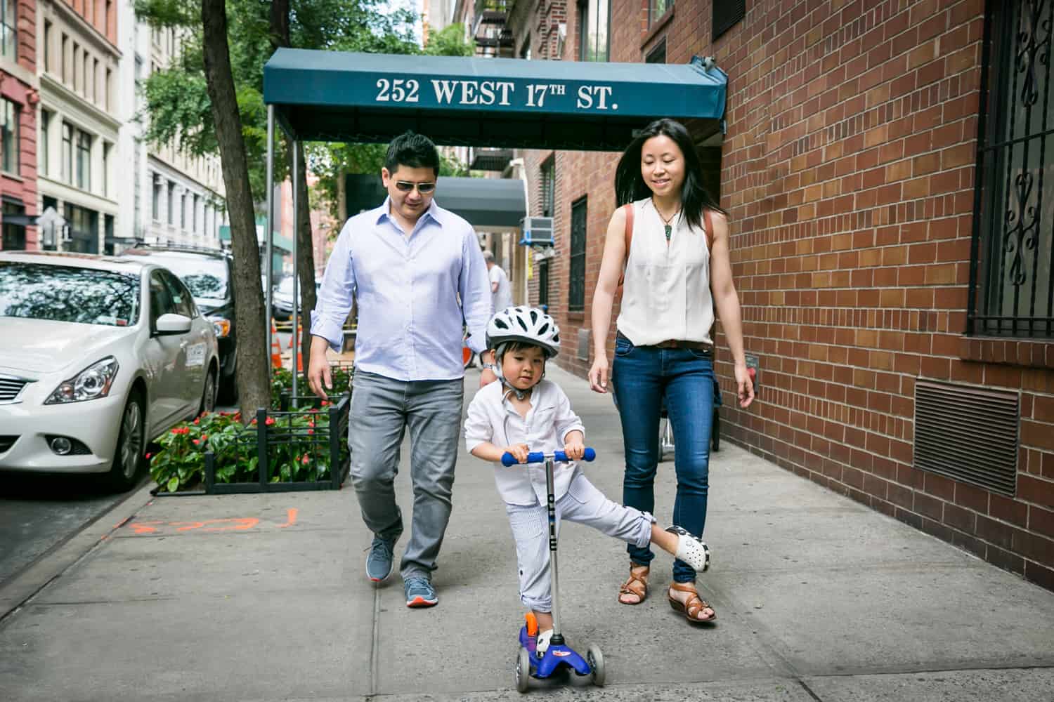 Parents and little boy on scooter on Manhattan sidewalk